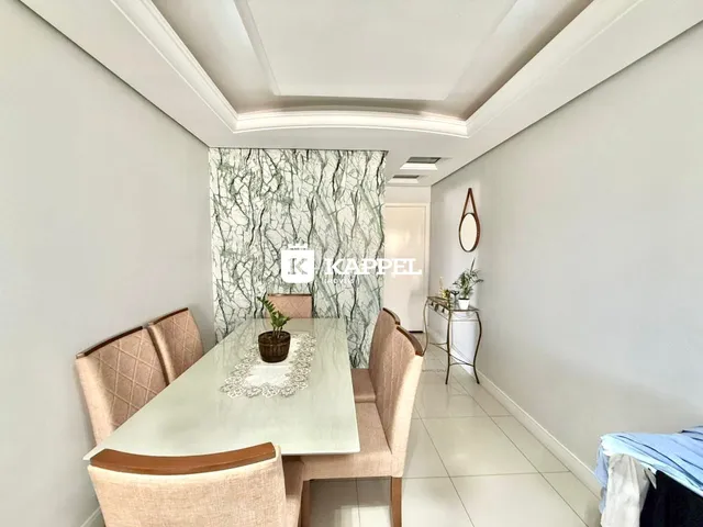 Sala de jantar com mesa e cadeiras em um ambiente claro com parede decorada.