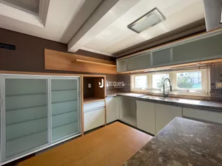 Imagem de uma cozinha com armários de madeira e janelas em Lajeado.