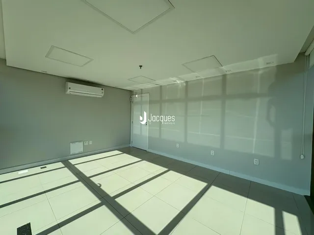 Ambiente interno de uma sala com piso claro e paredes cinzas.