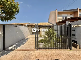 Vista externa da propriedade com portão de ferro e paisagismo.