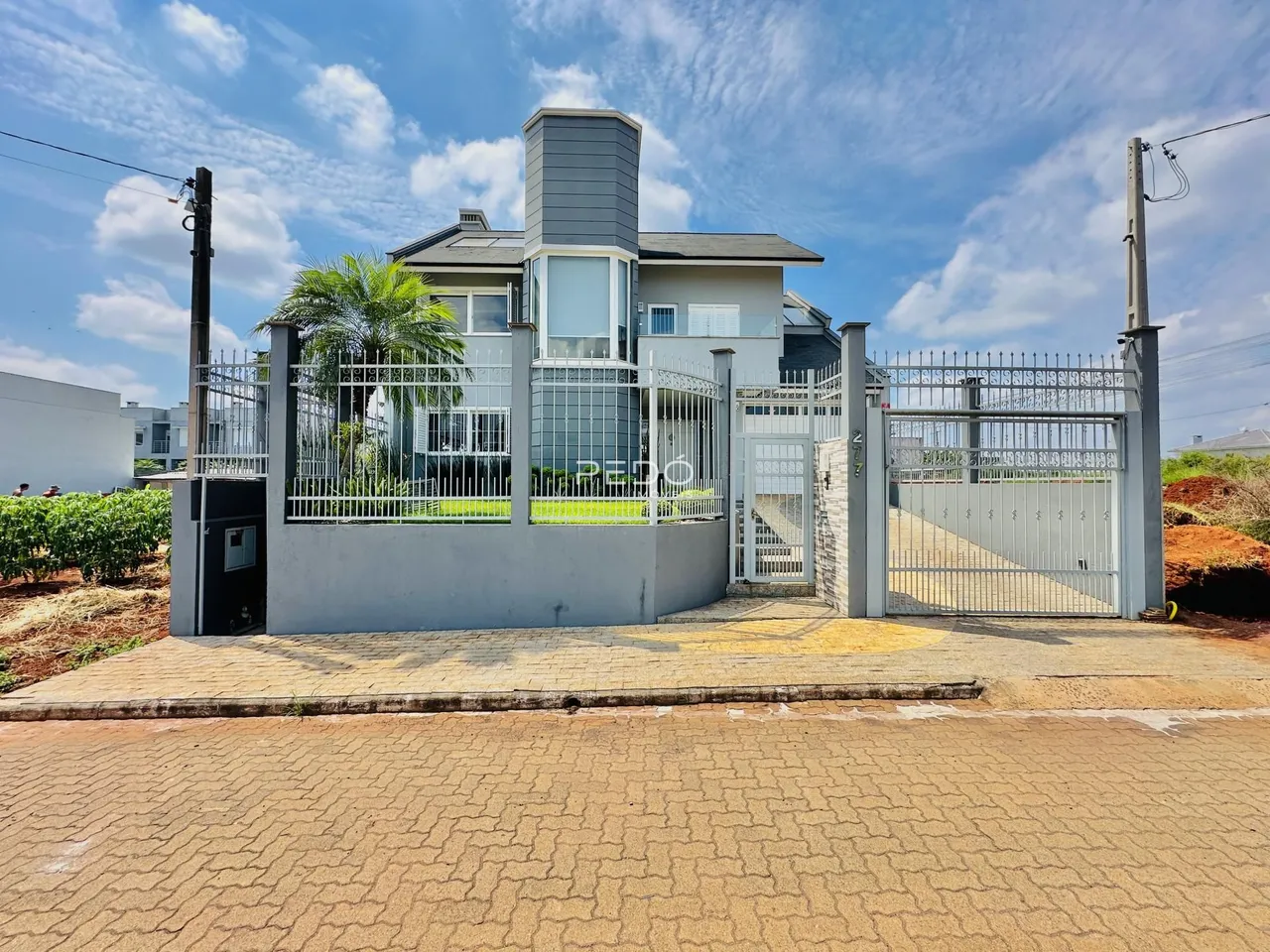 Fachada de uma residência em Lajeado, Brasil, com portão de ferro e muro.
