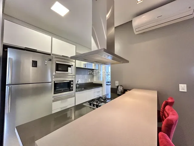 Uma cozinha moderna com armários brancos e eletrodomésticos de aço inoxidável.