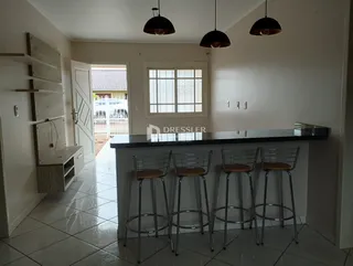 Interior de uma sala de estar com bancada e cadeiras em um imóvel no Brasil.
