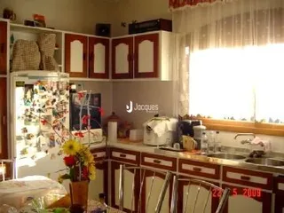Interior de uma cozinha com armários de madeira e janela iluminada.