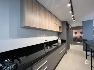 Esta é uma foto de uma cozinha moderna com armários de madeira clara e bancada escura.
