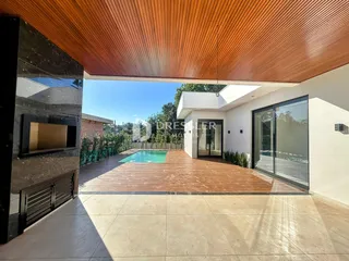 Vista da fachada de uma residência com piscina e deck de madeira.