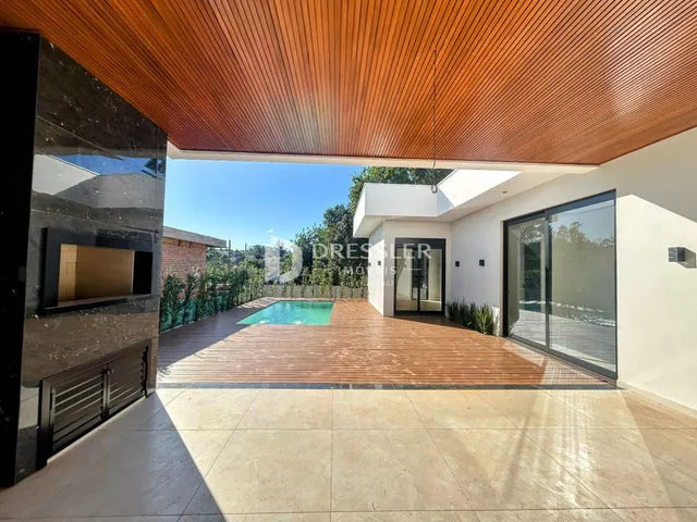 Vista da fachada de uma residência com piscina e deck de madeira.