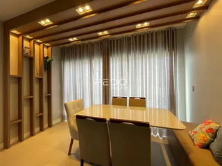 Vista de uma sala de jantar com decoração em madeira e cortinas claras.