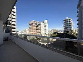 Vista da varanda de um apartamento em Lajeado, mostrando edifícios ao fundo sob um céu azul.
