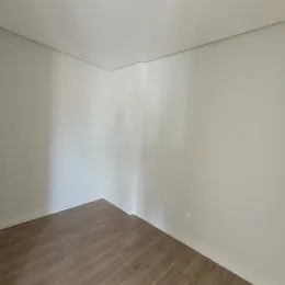 Parede branca e piso de madeira visíveis no interior da propriedade.