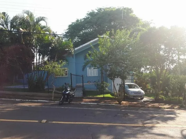 Fachada de uma residência azul em Lajeado, Brasil, com vegetação ao redor.