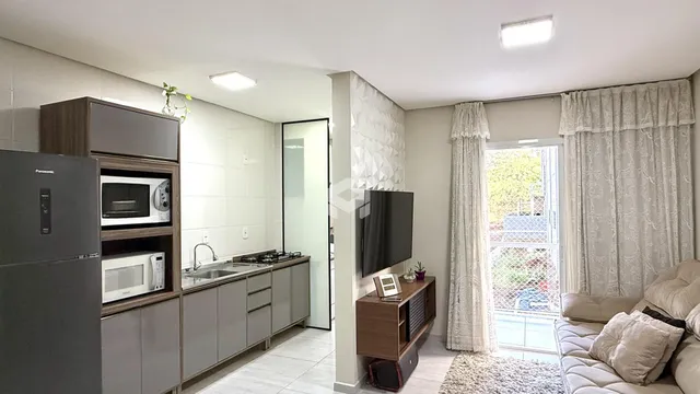 Sala de estar com cozinha integrada e vista para o exterior.