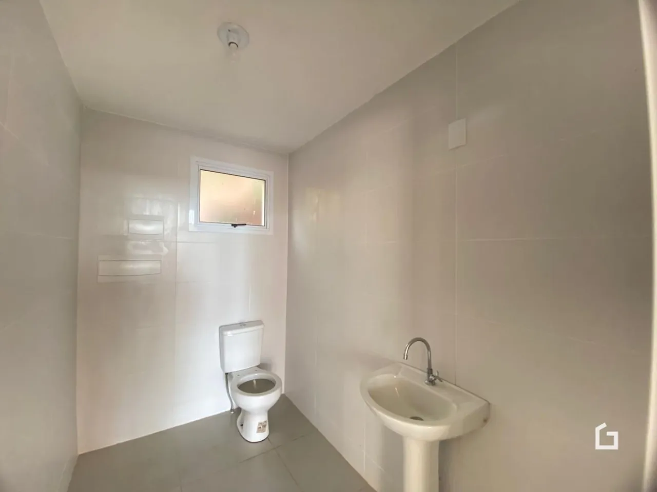 Um banheiro com paredes brancas e louças sanitárias instaladas.