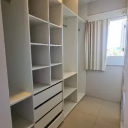 Foto de um corredor com estantes brancas e armários embutidos.