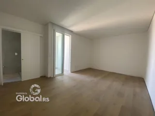 Ambiente interno amplo com piso de madeira clara e paredes brancas.