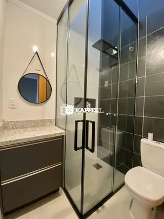 Banheiro com box de vidro e bancada de granito.