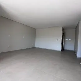 Vista interna de um ambiente amplo com piso claro.