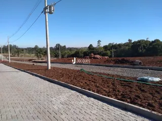 Vista da propriedade com terra exposta e vegetação ao fundo.