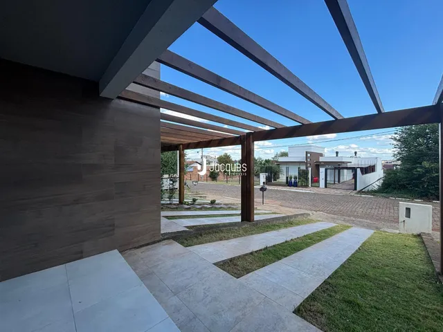 Vista da fachada de uma residência com estrutura de madeira e área externa pavimentada.