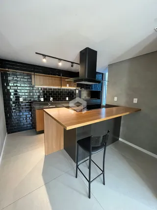 Foto de uma cozinha moderna com ilha de madeira e revestimento preto.