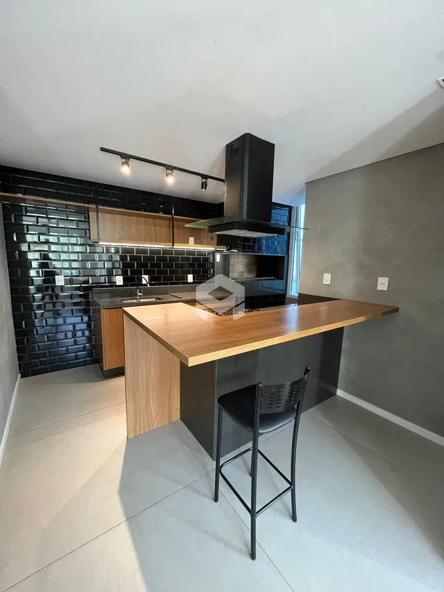 Foto de uma cozinha moderna com ilha de madeira e revestimento preto.