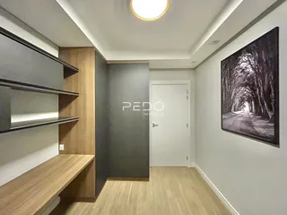 Uma sala de estar com piso de madeira clara e estantes embutidas.