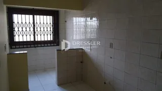 Interior com paredes de azulejo branco e janela com grades de ferro.