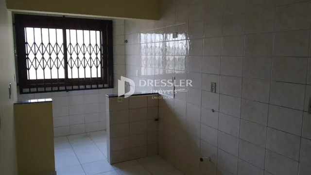Interior com paredes de azulejo branco e janela com grades de ferro.