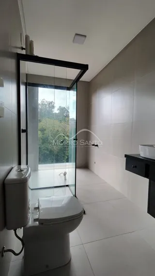 Banheiro com revestimento branco e porta de vidro que dá para a área externa.