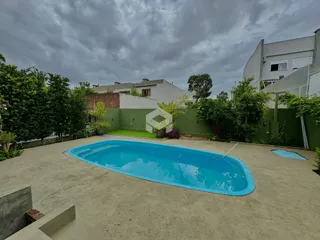 Foto de uma piscina externa com área verde no quintal.
