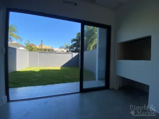 Vista externa de um gramado e muro através de uma porta de vidro.