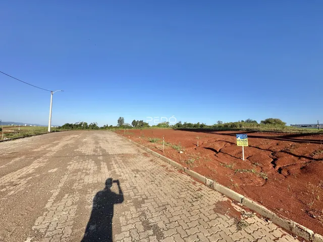 Uma estrada pavimentada se estende por um campo de terra vermelha sob um céu azul claro.