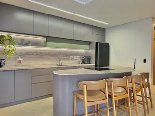 Vista da cozinha moderna com ilha e armários em tom de cinza.