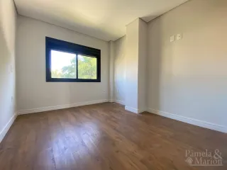 Foto interna de um cômodo com piso de madeira e uma janela.