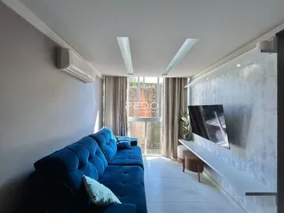 Sala de estar com sofá azul e janela iluminada.