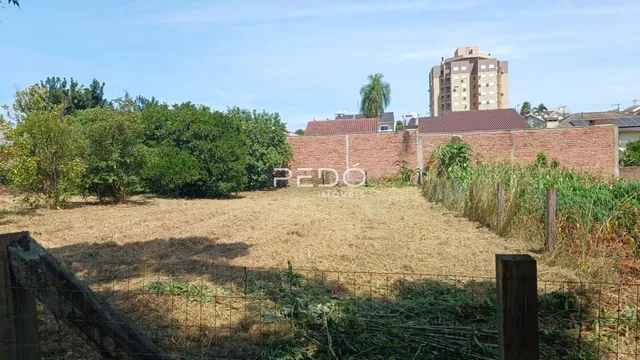 Vista externa de um terreno com cerca e muro de tijolos.