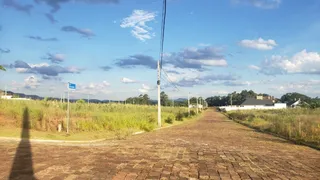 Vista externa de uma área pavimentada com vegetação seca sob um céu azul.