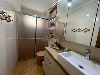 Banheiro com bancada branca e revestimento de azulejos claros.