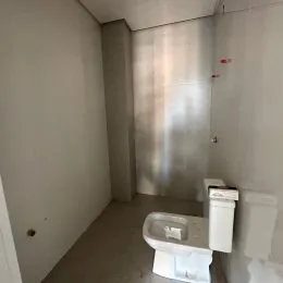Foto interna de um banheiro com revestimento branco.