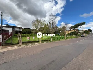 Vista externa de uma rua em Lajeado, Brasil, com vegetação e sinalização imobiliária.
