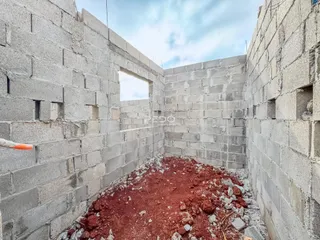 Vista interna de paredes de concreto em construção com piso de terra.