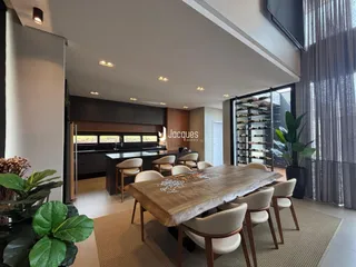 Sala de jantar e cozinha com mesa de madeira e armários escuros.