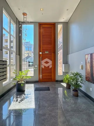 Hall da entrada de um apartamento moderno com piso de mármore e grandes janelas.