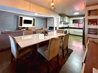 Foto de uma sala de jantar com mesa de madeira e cozinha moderna.