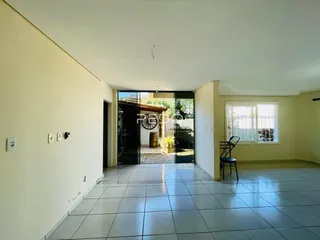 Vista interna de um ambiente com piso de cerâmica e portas de vidro que dão acesso ao exterior.
