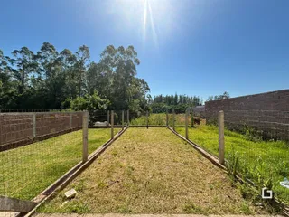 Vista de um terreno gramado cercado por cerca de arame.