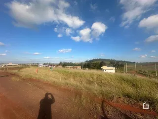 Paisagem rural com campo aberto e estrada de terra no horizonte.