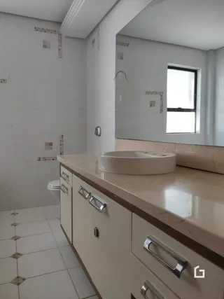 Foto de um banheiro com bancada e armários brancos.
