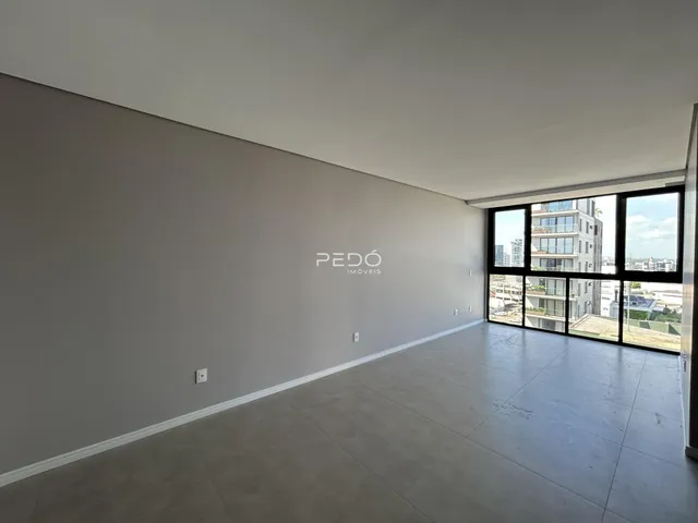 Interior de um espaço amplo com paredes brancas e piso cinza claro.