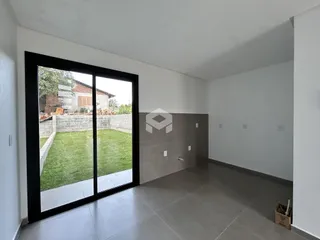 Uma vista interna com porta de vidro que se abre para um quintal gramado.